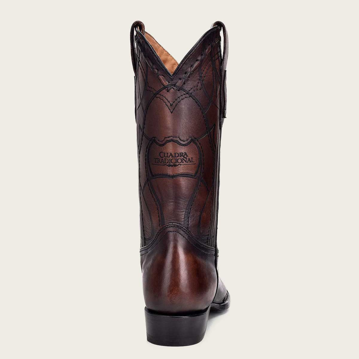 An intricately engraved brown leather western boot with pointed toe and stacked heel, perfect for a stylish and rustic look