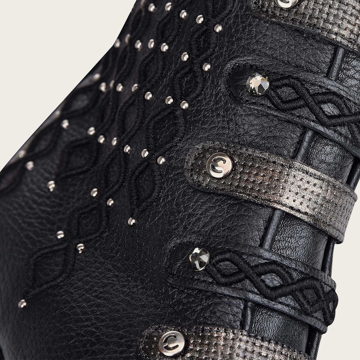 An image of a black leather bootie with intricate embroidery details and sparkling Austrian crystals