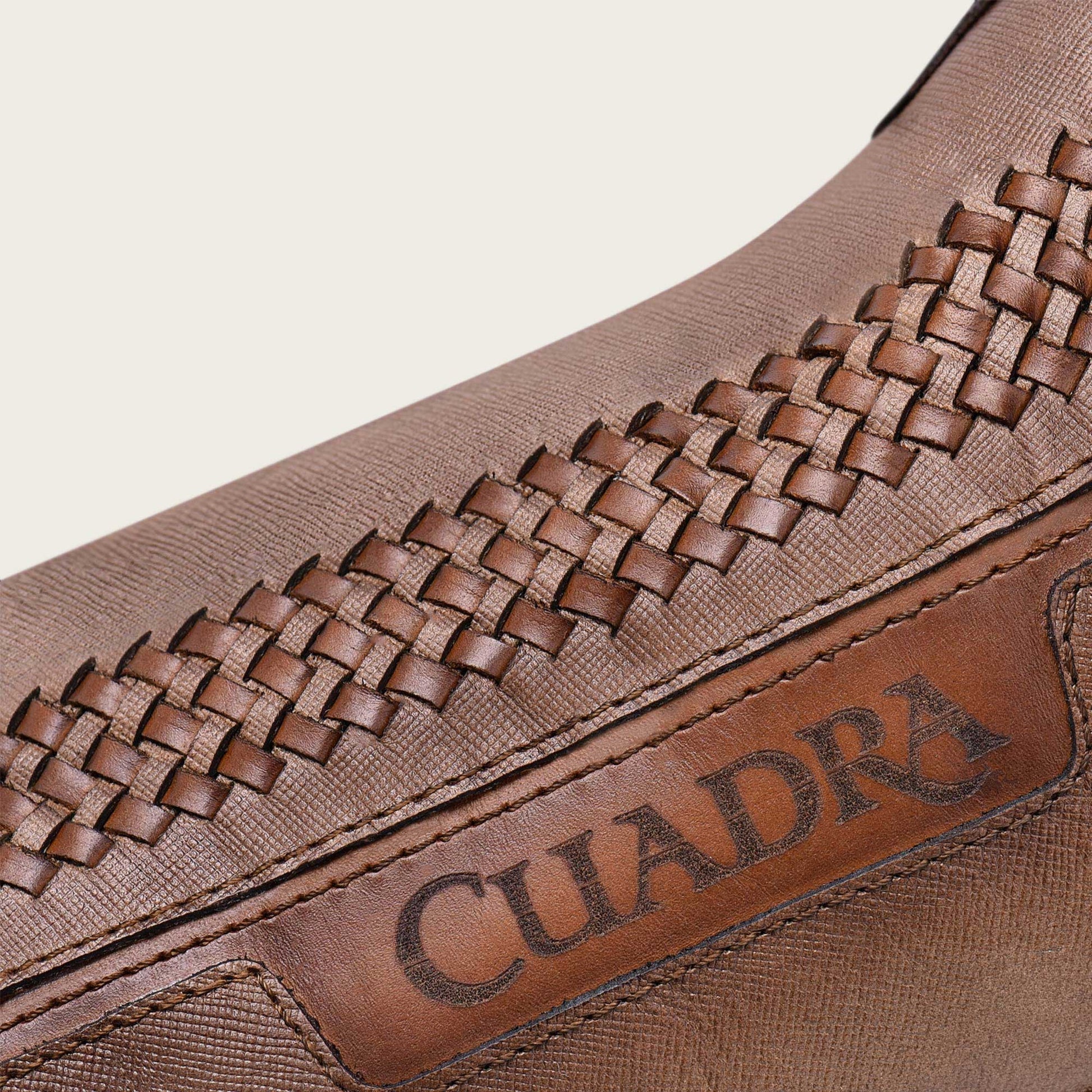 A skillfully crafted boot made of honey-colored leather with intricate handwoven details