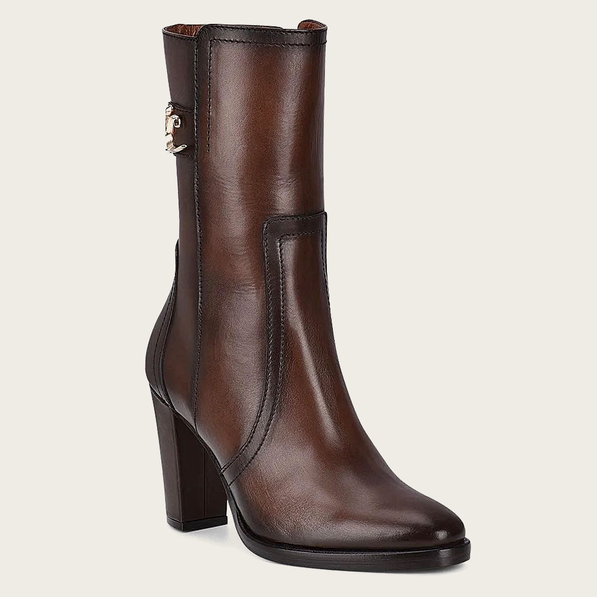 Brown leather bootie with metallic symbol on side. Smooth, polished leather, block heel, high ankle shaft, intricate design.